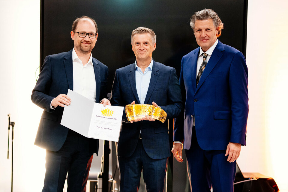Ralf Pahlsmeier, Geschäftsfüher Ahorn-Sportpark gGmbH (stehend links), hält die Urkunde für den Preisträger des goldenen Ahornblattes. In der Mitte steht goldene Ahornblatt-Preisträger Dr. Uwe Kern mit dem Goldenen Ahornblatt. Daneben steht Martin Nixdorf (Stiftung Westfalen, rechts im Bild).