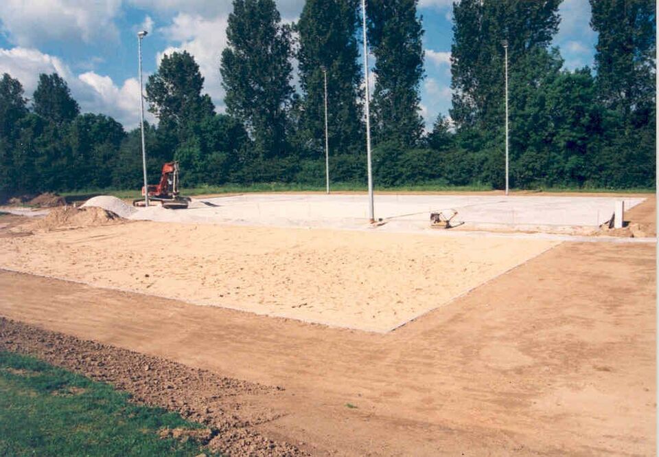 Bau eines Beachvolleyballfeldes mit Sand und nebenan eines Kunstrasenplatzes für Fußball mit einer Lichtanlage.